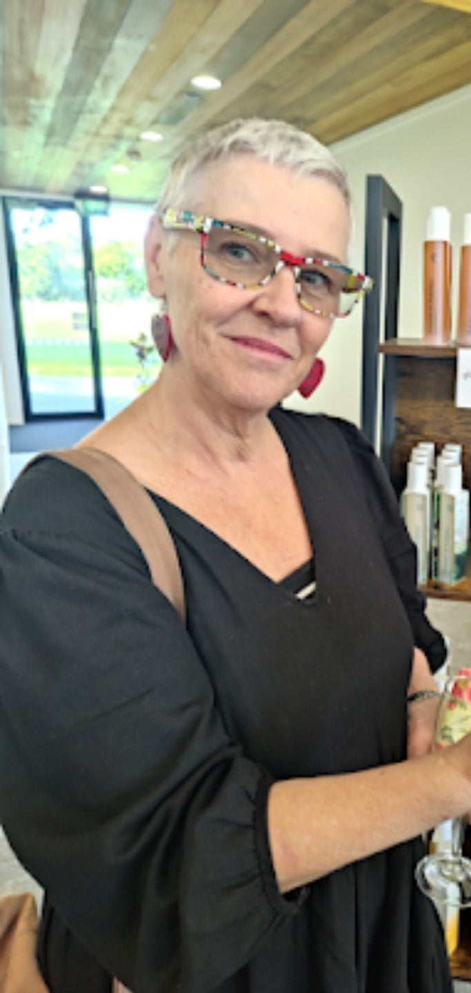 Woman holding a product in a store with shelves of skincare items.